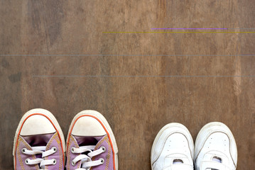 Big and small shoes on wooden floor.