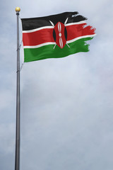 Fototapeta na wymiar Worn and tattered Kenya flag blowing in the wind on a cloudy day
