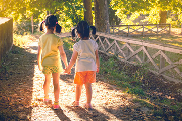 Obraz premium Anonymous girls holding hands in park