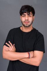 Young handsome Indian man against gray background