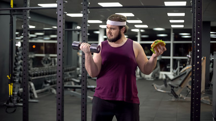 Fototapeta na wymiar Obese male choosing between sport and fast food, burger addiction and motivation