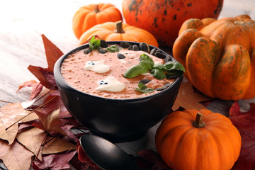 Roasted pumpkin and carrot soup with cream and pumpkin seeds on wooden background.