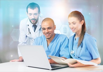 Successful medical doctors using a laptop and smiling while