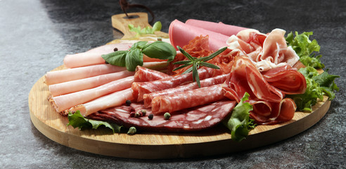 Food tray with delicious salami, pieces of sliced ham, sausage and salad. Meat platter with selection.