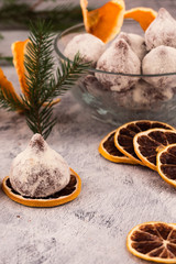 Chocolate truffles sprinkled with powdered sugar, slices of dry lemon, spruce branch with green needles, Christmas decorations.