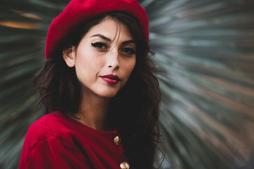 Pretty and confident young woman displaying French fashion in the form or a red beret