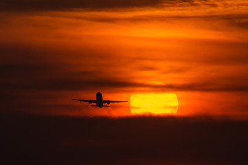 Air plane taking off at sunset near to the sun with beautiful red cloud in background