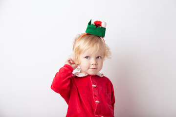 Portrait of cute cute baby girl 1.5 years old, in red clothes And in the cap of the gnome helper Santa.close-up on a white light background. concept christmas