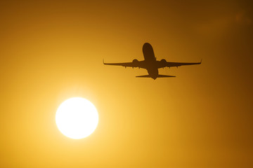 Silhouette of an air plane near to the sun with beautiful red clouds in background