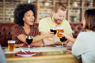 Friends making a toast while sitting in restaurant. Multi-ethnic group.