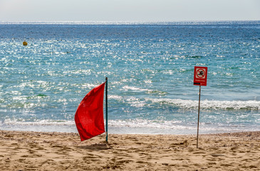 "No Swimming" sign and Red flag on the beach of Palma de Mallorca - Balearic Islands, Spain. © UlyssePixel
