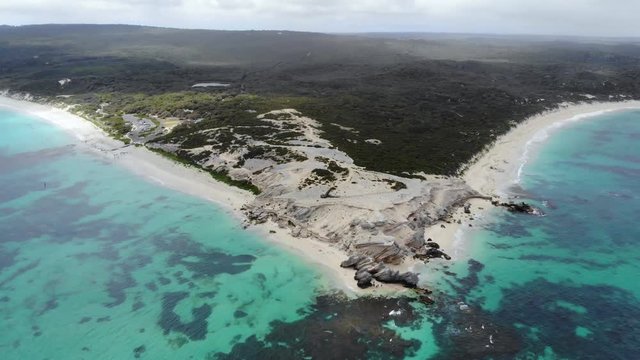 drone view flying backwards over the turquoise contrasting ocean and white sand beaches and green bush of the mainland in plain sight