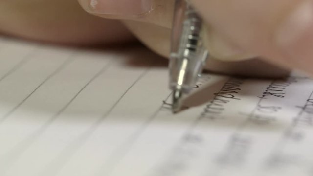 Close up shot of a hand holding a pen writing an essay in an exam.