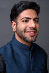 Fototapeta premium Young handsome Indian businessman against gray background