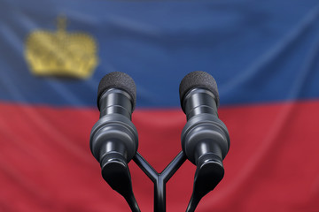 Podium lectern with two microphones and Liechtenstein flag in background