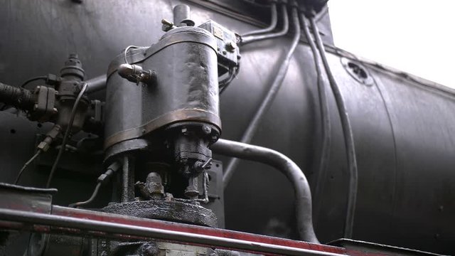 Detail shot of steam train engine with smoke. Black train composition, waiting on a station.