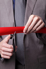 Businessman cutting red ribbon at inaugural event