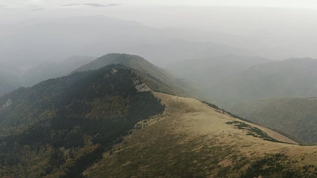 Ascending aerial shot of foggy peak covered with few evergreens, Slovakia