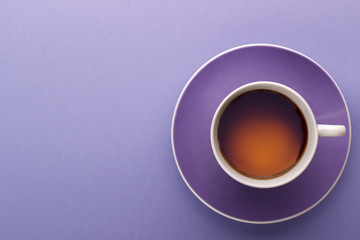 Hot cup of tea or coffee on lilac table copy space close up top view