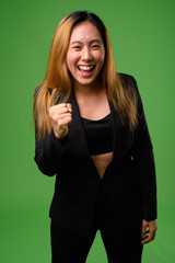 Portrait of young Asian businesswoman against green background