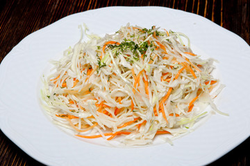 Homemade, crispy cabbage and carrot salad is made in a traditional way and decorated with herbs and peppers.