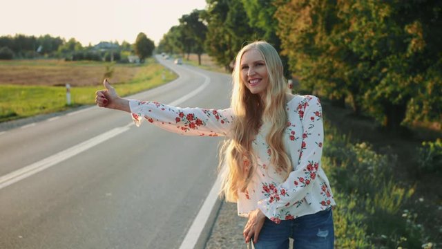 Young woman hitchhiking on countryside road.
