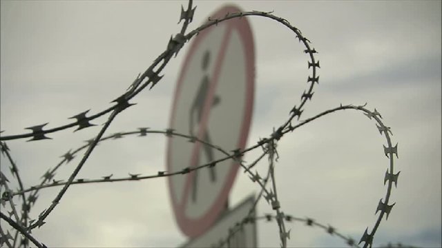 No Entry Sign with Barbed Wire and Razor Wire Security or Border Fence