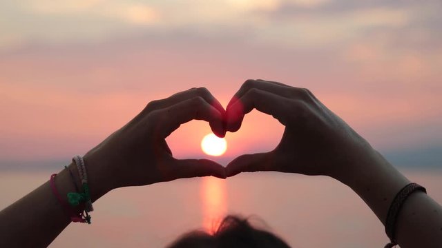 Girl shapes hands to a heart during sunset on a lake.
Shot in 4k at 60fps so the clip can be slowed down if desired.
Shot at Garda Lake in Italy