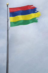 Worn and tattered Mauritius flag blowing in the wind on a cloudy day