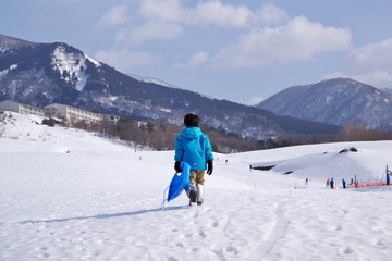 Fototapeta na wymiar スキー場でそり遊びをするキッズ