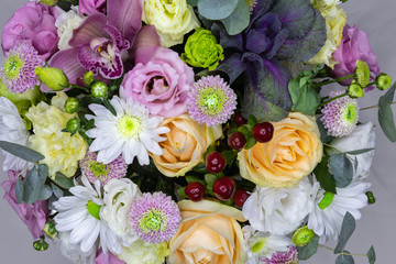 background. beautiful flowers (roses, daisies ...) in a white cardboard gift box stand on a wooden table