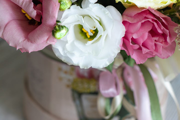 background. beautiful flowers (roses, daisies ...) in a white cardboard gift box stand on a wooden table