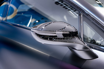 Silver side view mirror with silver modern car. Close up.