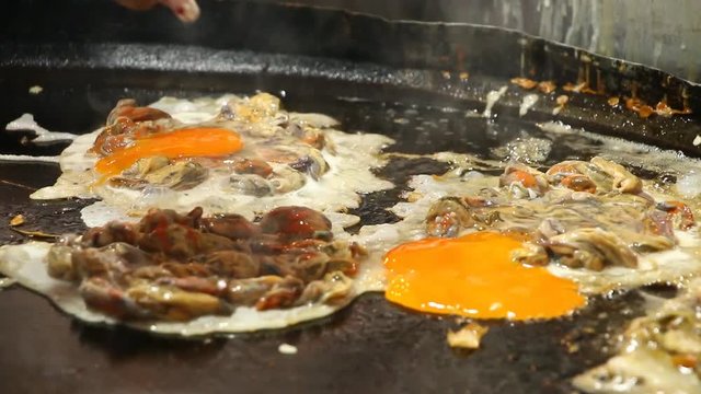 frying  oyster omelette in pan , Thai street food
