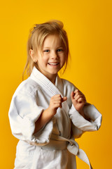 The karate girl on a yellow background with white belt is hitting right hand