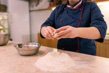 Hard-working baker. Hard-working baker wearing blue jacket making dough for croissants early in the...