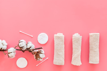 Cotton hygiene products. Cotton pads and swabs, towels twisted coil near dry cotton flowers on pink background top view copy space
