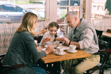 Cute girl. Blonde-haired grandmother taking care of her beautiful cute girl spending morning in cafeteria