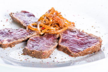 slices of roast beef with onions on a white background