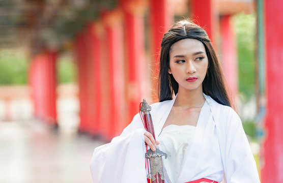 Beautiful Chinese woman with a traditional suit with a sharp sword in her hands, Beautiful and belligerent face, Young woman with a samurai bushido katana sword