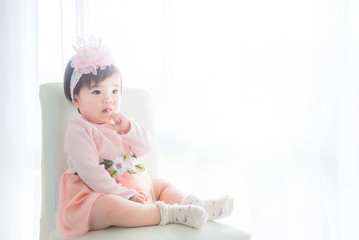 Little asian cute girl sitting on the chair in front of bright window
