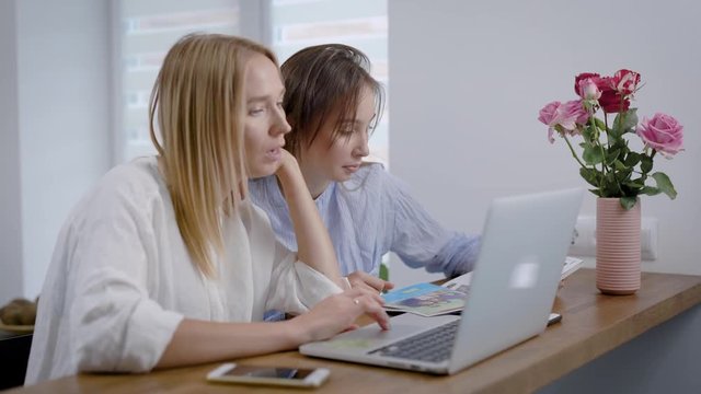 Women reading magazine and using laptop