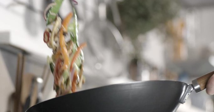 Stir fry vegetables being tossed in a wok. Slow motion.