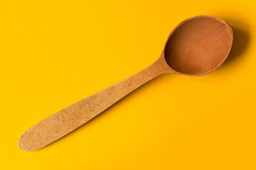 Old wooden spoon. Isolated on yellow background