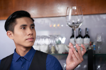 Clean crystal glass in hand of young handsome waiter