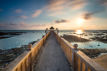 Fototapeta premium A Long exposure picture of golden sunrise with stone jetty