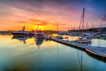 A majestic sunrise with boat resting near   the dock as foreground at Putri Harbour, Iskandar...