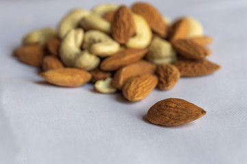 An almond isolated from a heap of other nuts like almonds and cashew