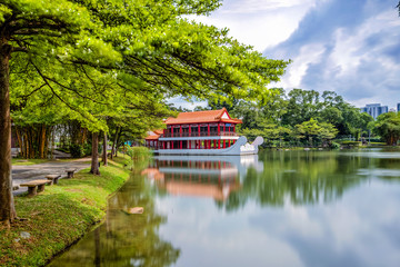 Yao-Yueh Fang Stone boat structure in a pound in Chinese Singapore garden with blue cloudish and reflection