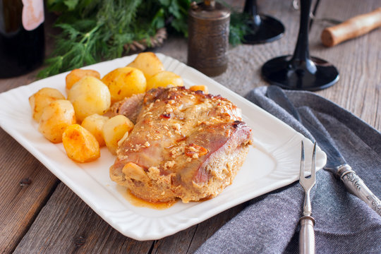 Baked turkey thigh meat with potatoes on a white dish, horizontal